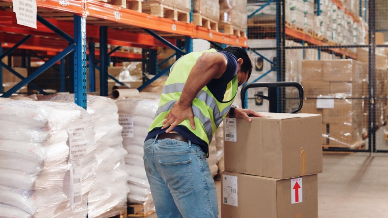Warehouse worker experiencing back pain during repetitive task
